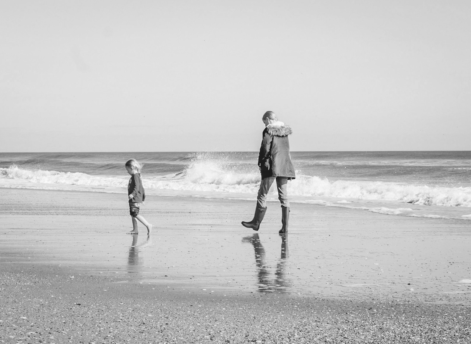 Förälder och barn som går längs stranden